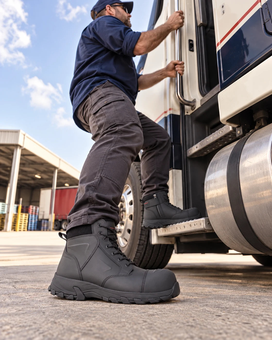 Truck driver wearing Helium Black boots beside a parked truck at an Australian depot